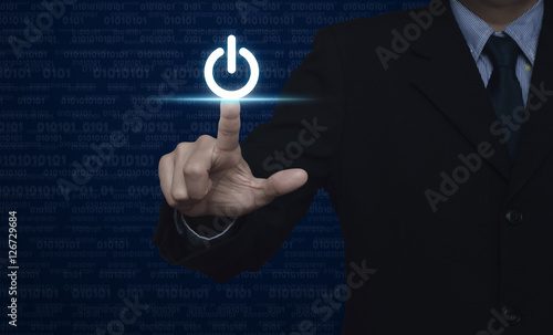 Businessman pressing power button over computer binary code blue