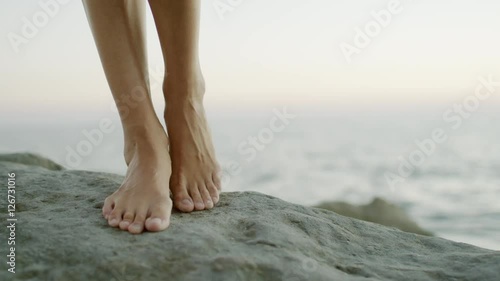 female feet against the sea on the rock