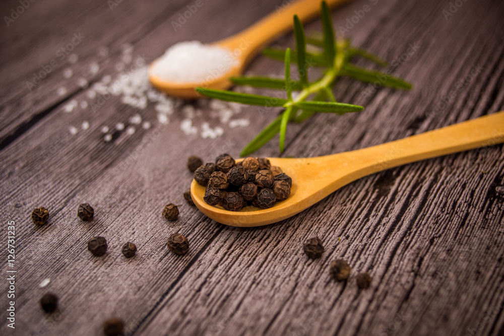 salt, rosemary and black pepper on wooden table salt, rosemary and black pepper on wooden table