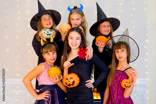 Happy group of teenagers in Halloween costumes posing on camera