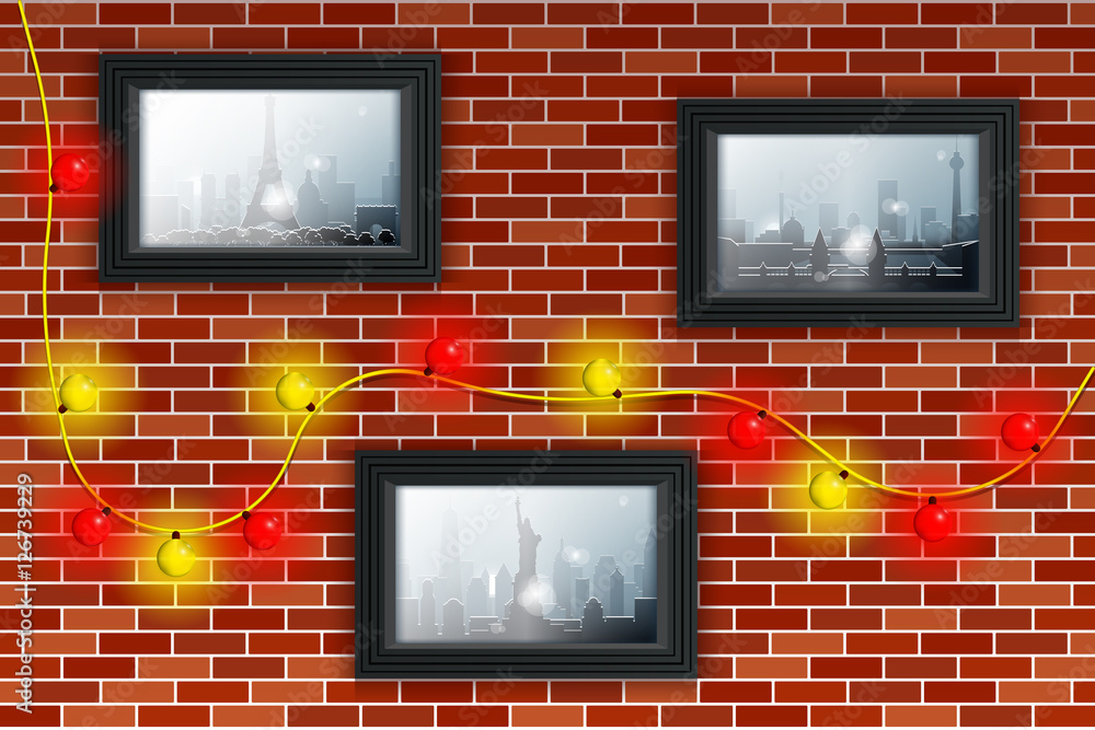 Decorated brick wall with Christmas lights and photos. Winter and snowfall in different cities illustrated in the photos. Pictures in gray frames.