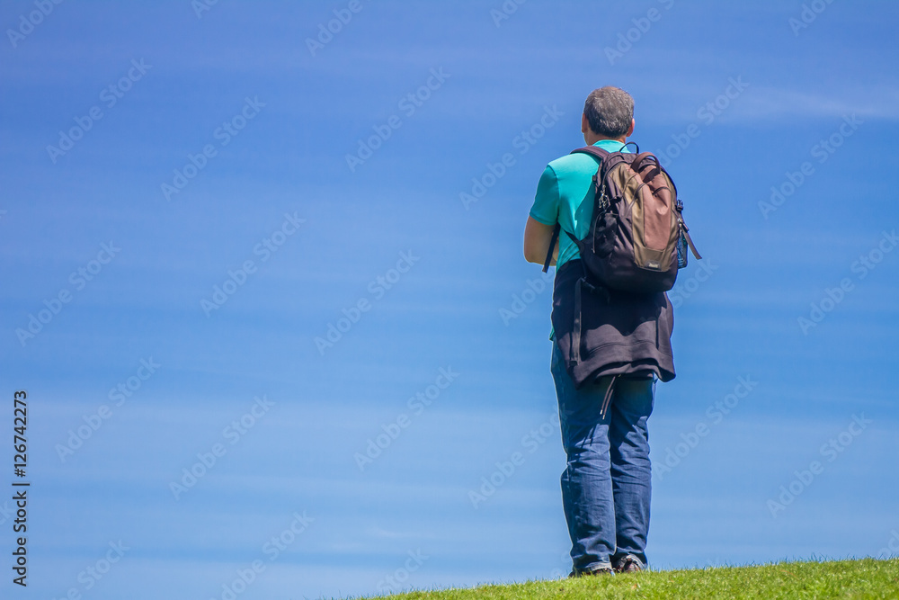 Young Man Traveler with backpack relaxing outdoor with blue on b Young Man Traveler with backpack relaxing outdoor with blue on b