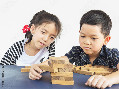 Children is playing jenga  a wood blocks tower game for practicing their physical and mental skill