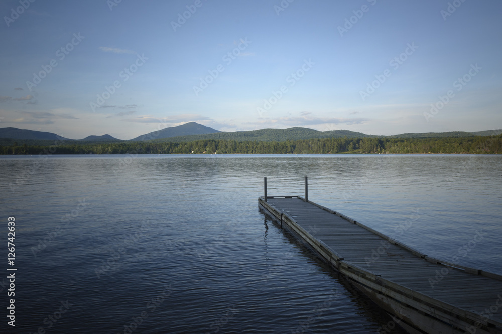 A pier extends into the lake on a calm summer afternoon