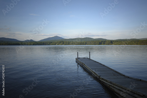 A pier extends into the lake on a calm summer afternoon