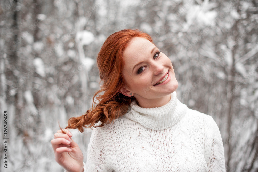 Ginger cute girl in white sweater in winter forest. Snow december in park. Christmas time. Happy New Year poster with beautiful woman. Ginger cute girl in white sweater in winter forest. Snow december in park. Christmas time. Happy New Year poster with beautiful woman.