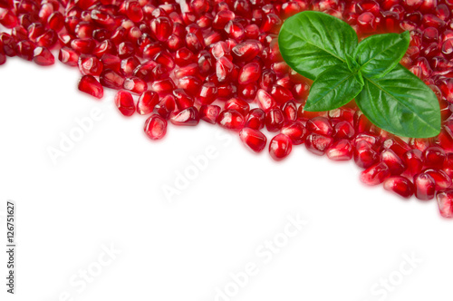 Background made of red pomegranate seeds with basil. The scattered red grains of a pomegranate. Top view.