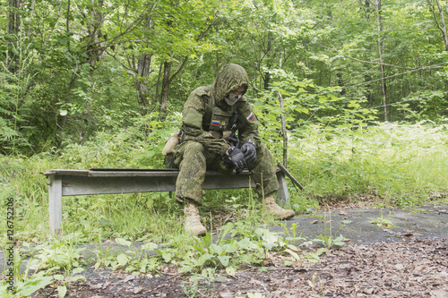 The soldier in field uniform and a mask sitting on a bench