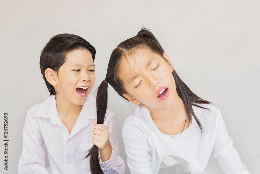 Lovely Asian couple school kids playing together, 7 and 10 years old, over gray background Lovely Asian couple school kids playing together, 7 and 10 years old, over gray background