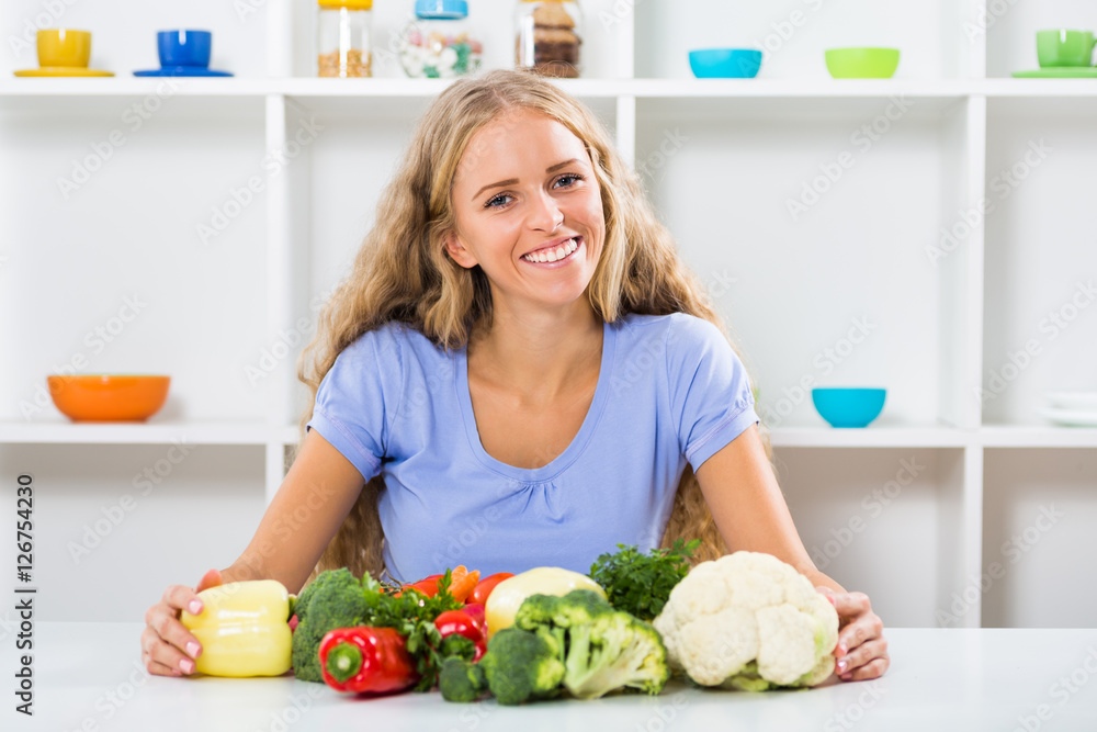 Beautiful girl is sitting at the table with bunch of vegetable.
Beautiful girl is sitting at the table with bunch of vegetable.