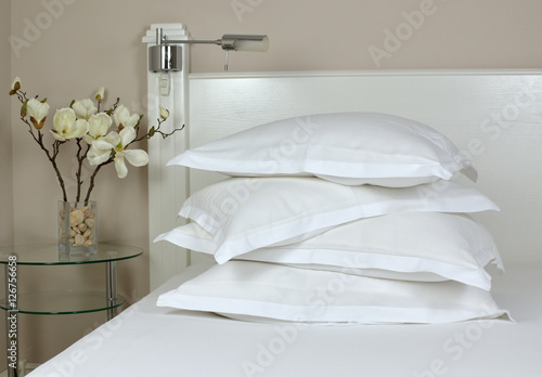 Принти на полотні Pile of comfortable pillows in white linen on a bedhead