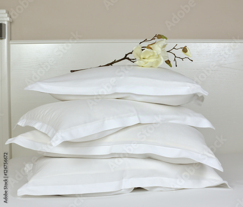 Foto Pile of comfortable pillows in white linen on a bedhead with artificial orchid d