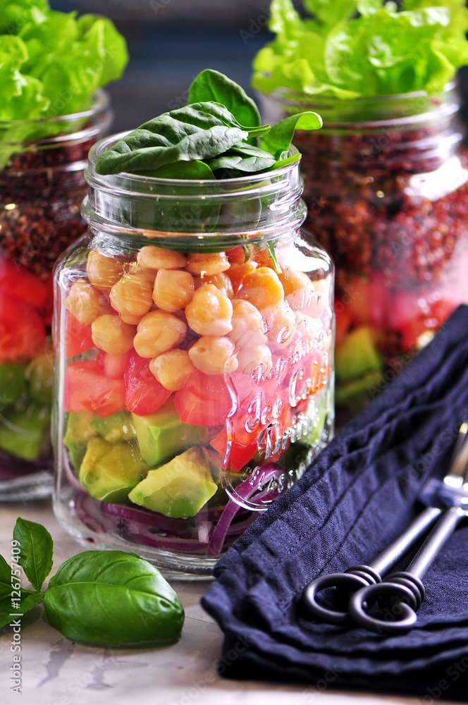 Healthy salad with quinoa and chickpeas, avocado, tomato, red onion, baby spinach, lettuce, olive oil in a Mason jars. Healthy salad with quinoa and chickpeas, avocado, tomato, red onion, baby spinach, lettuce, olive oil in a Mason jars.