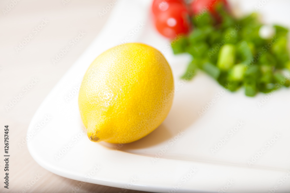 yellow lemon on a white plate with other vegetables