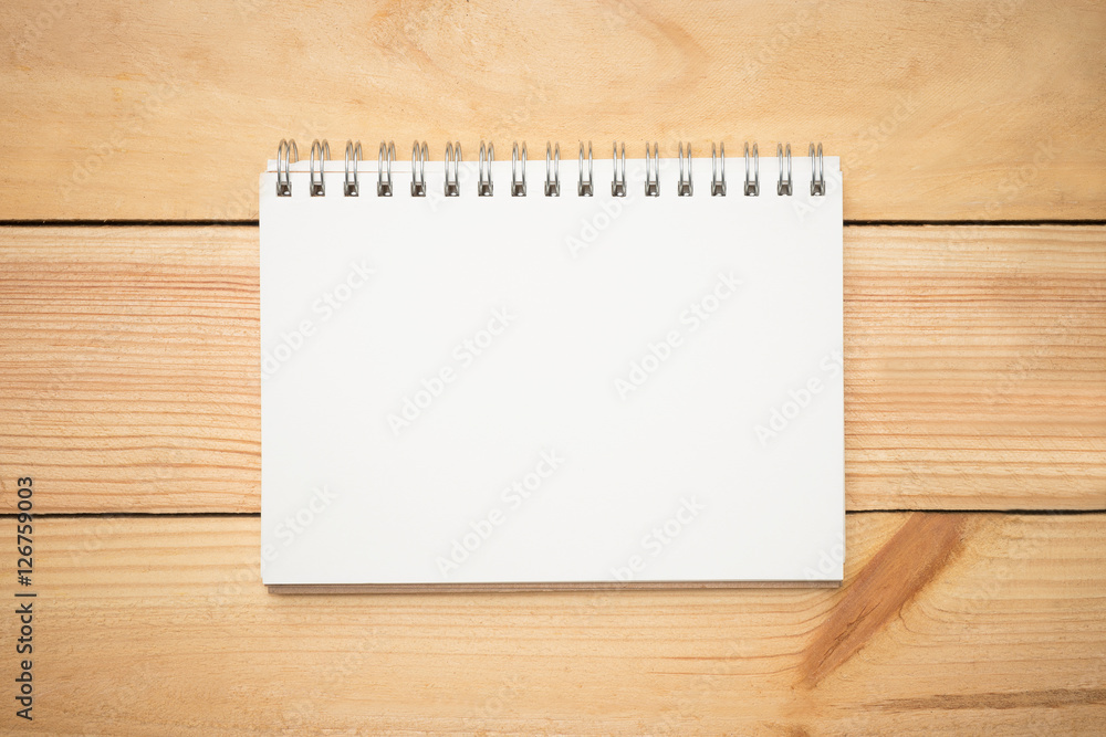 Blank notebook page in the middle of wood office desk table. Top view, flat lay. Blank notebook page in the middle of wood office desk table. Top view, flat lay.