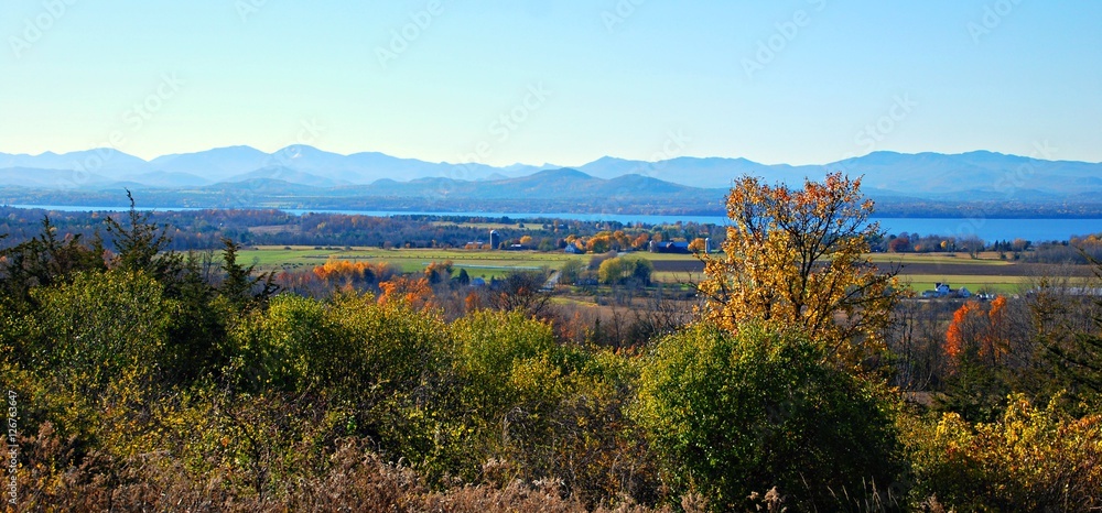 Naklejka premium Autumn Panorama of forests lake and mountains in rural setting