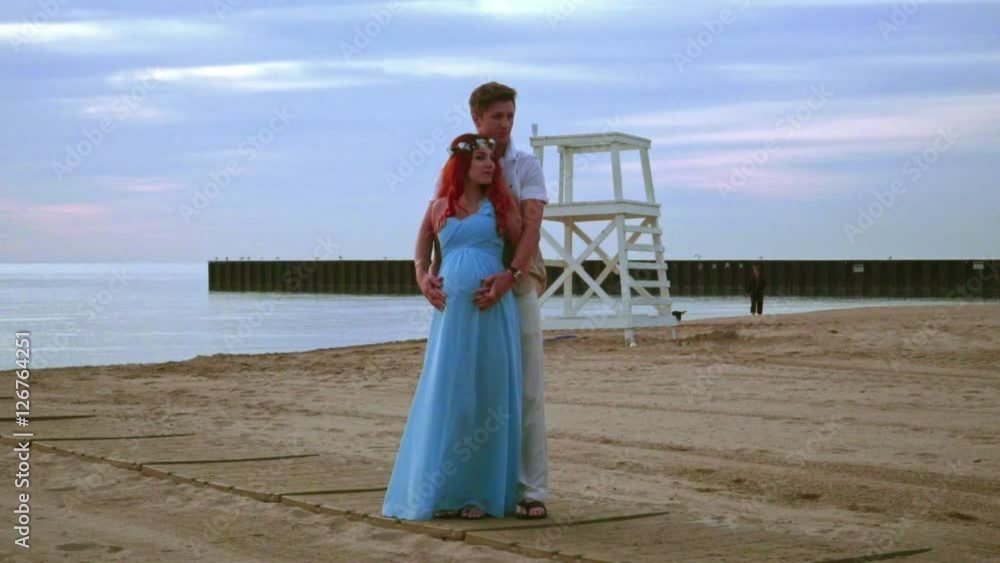 Vidéo Stock Pregnant couple on sea beach at sunrise. Love couple