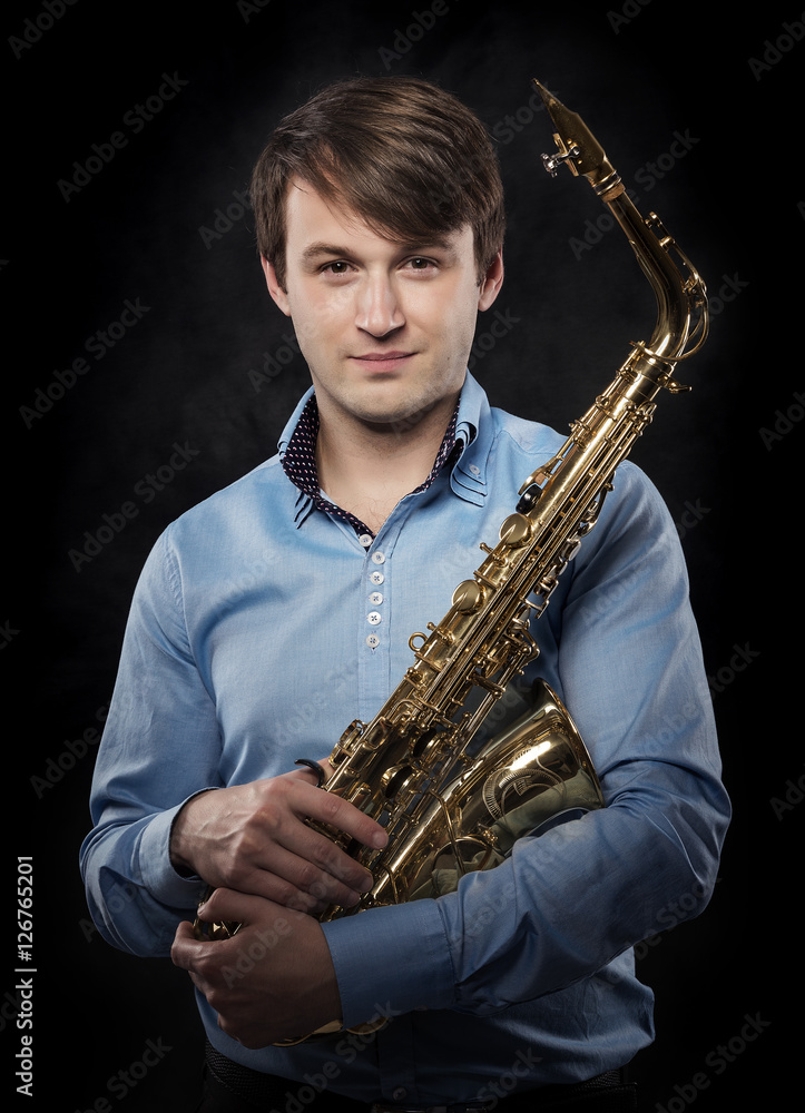 Fototapeta premium Attractive saxophonist on a dark background.