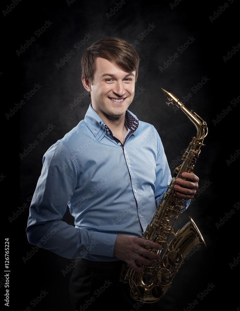 Fototapeta premium Attractive saxophonist on a dark background.