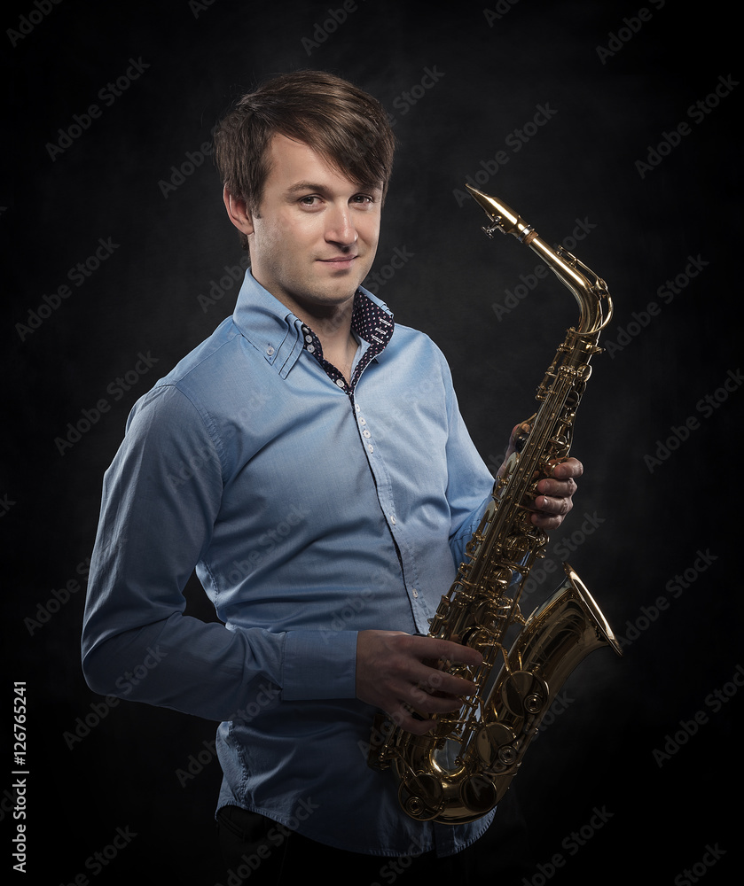 Fototapeta premium Attractive saxophonist on a dark background.