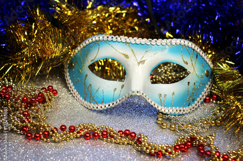 Brilliant blue carnival mask close up on shiny background with festive colored garlands