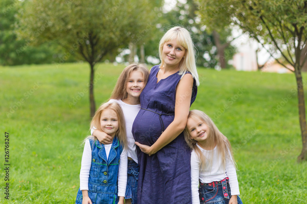 Fototapeta premium Young pregnant mother with her family in a park
