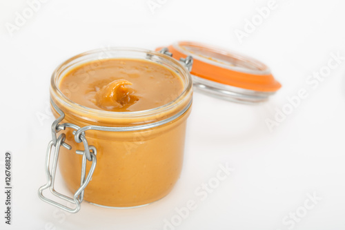 Creamy peanut butter in jar on white background