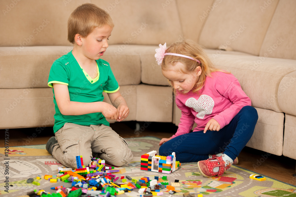 Obraz premium Children and their mother are playing with blocks on the ground