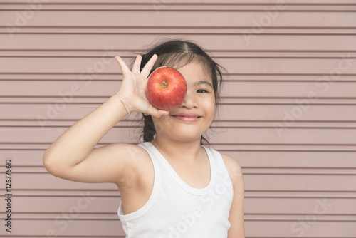 Little Asian girl enjoy eat an apple.