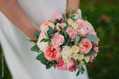 Fotografi beautiful delicate Bridal bouquet of cream roses in hands of bride