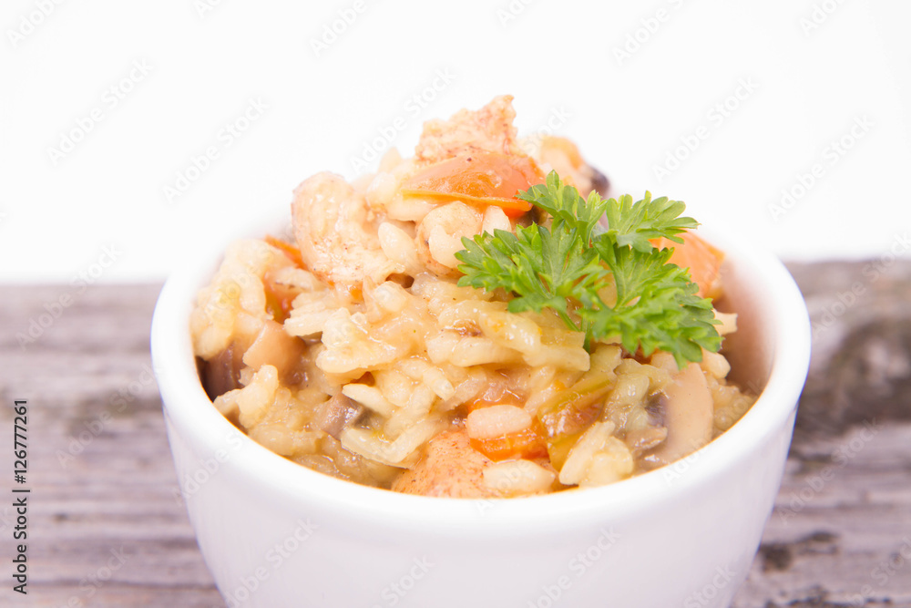 Risotto with chicken, bell pepper, onion, portobello and parsley on a wooden background Risotto with chicken, bell pepper, onion, portobello and parsley on a wooden background