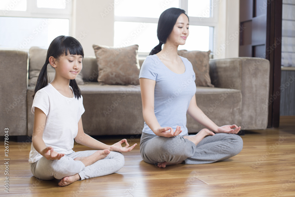 Young mother and daughter doing yoga at home Young mother and daughter doing yoga at home
