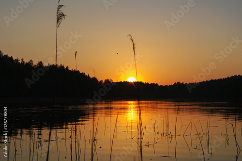 red and orange sunset over lake with water reflection