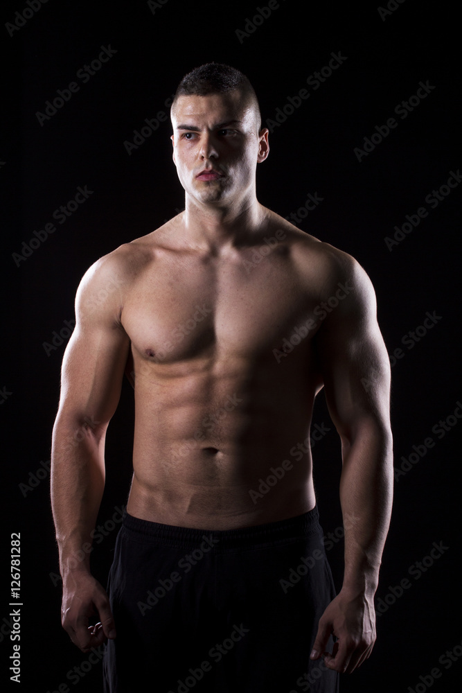 Fototapeta premium Strong young man showing his muscles