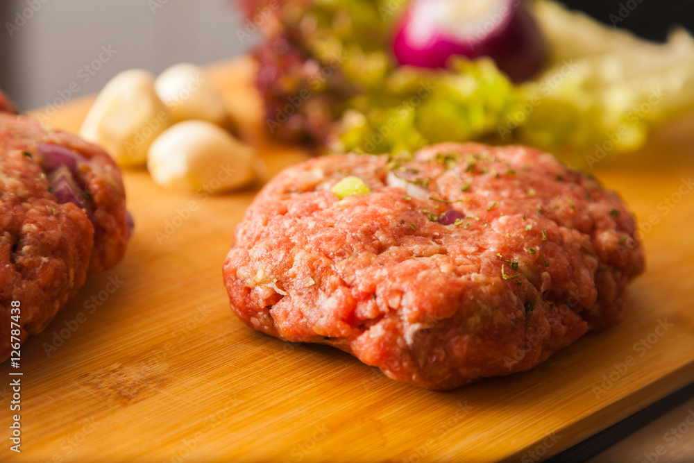 raw meat burger lies on a board