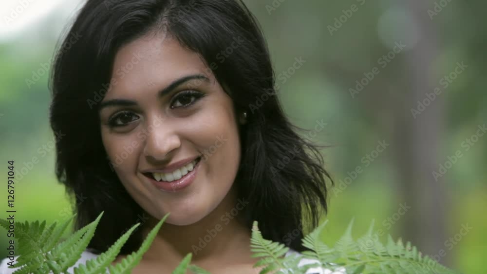 CU Portrait of young woman covering face with fern leaves / Singapore