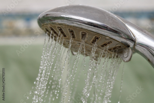 Closeup of shower head with flowing water splashing out, drops