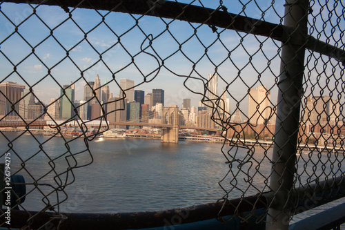 Brooklyn Bridge framed in a hole in a fence