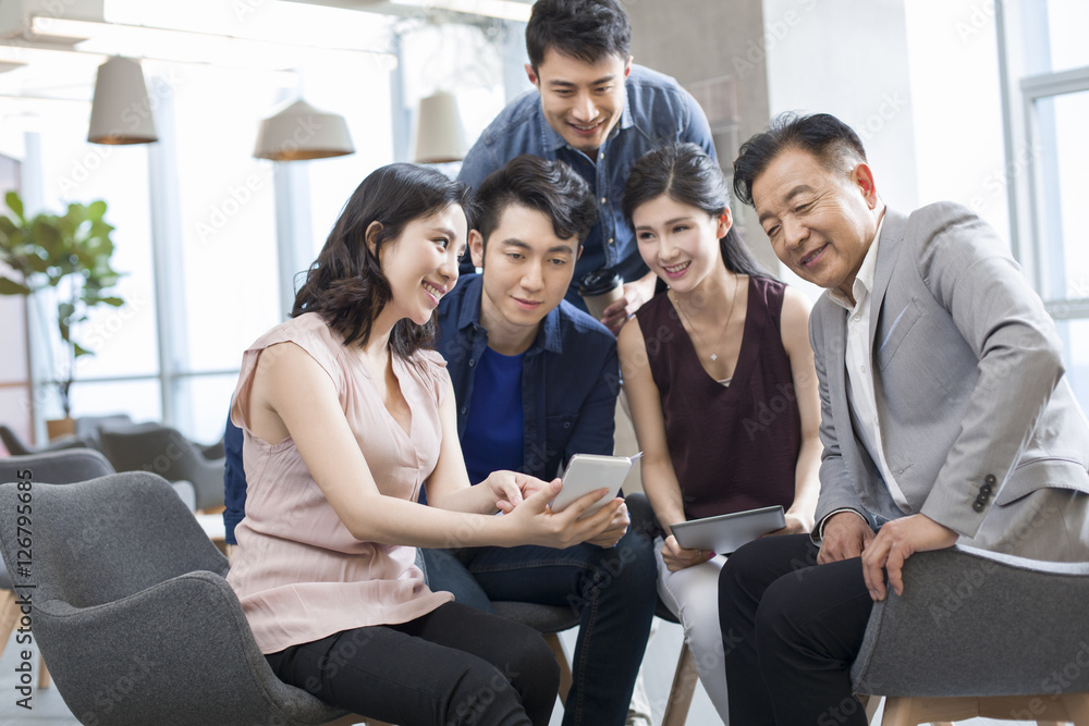 Businesswoman showing smartphone to colleagues in office