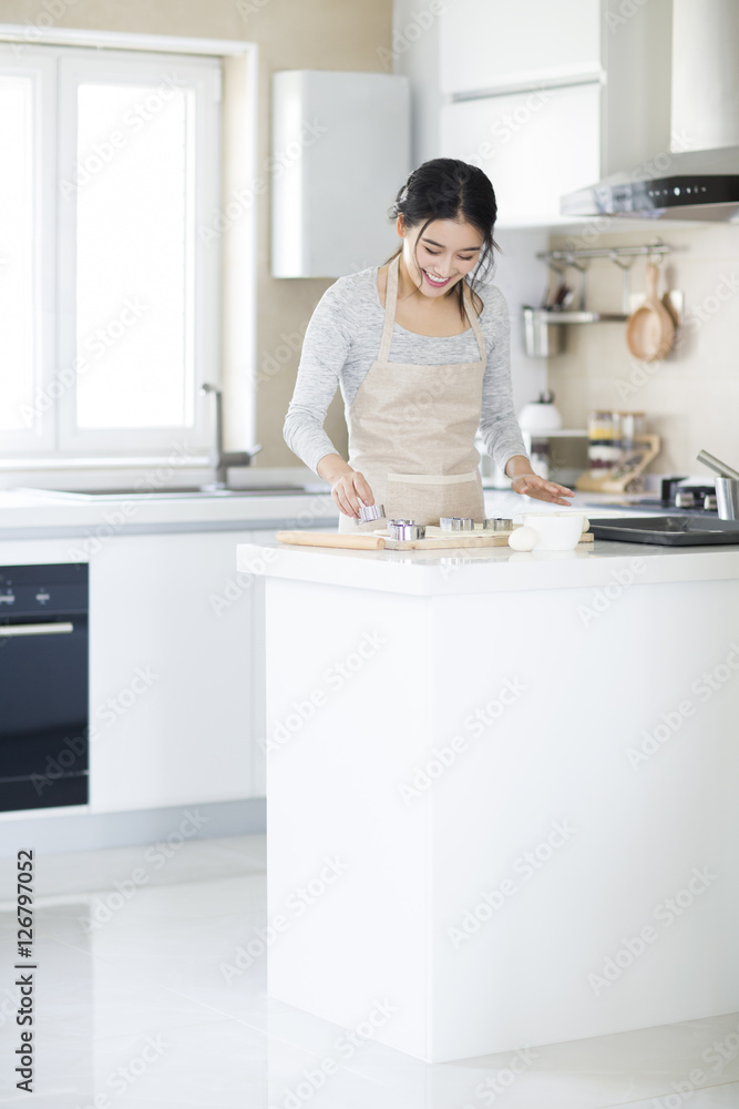 A smiling young woman making cookies in the kitchen A smiling young woman making cookies in the kitchen