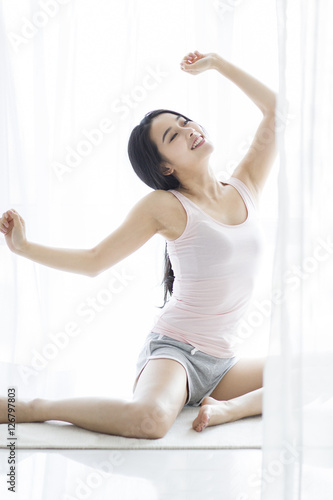 Happy young woman sitting on window sill