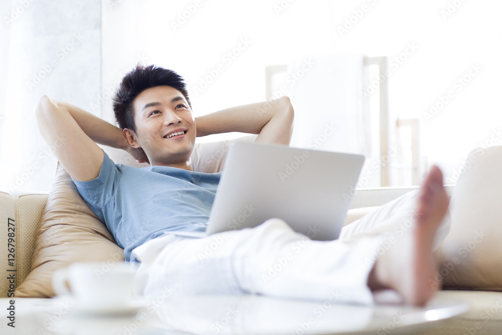 Young man using laptop on the sofa Young man using laptop on the sofa