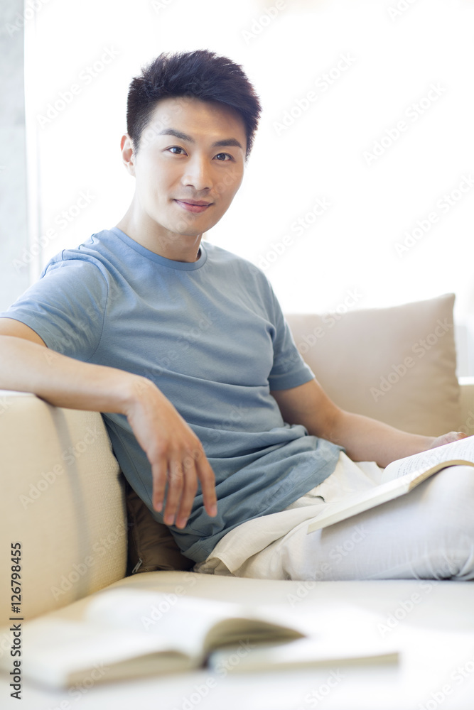 Young man reading a book on the sofa Young man reading a book on the sofa