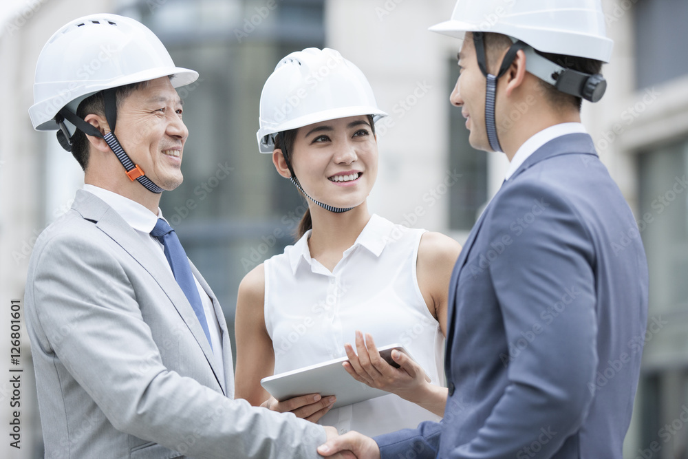 Confident architects shaking hands while standing outdoors Confident architects shaking hands while standing outdoors