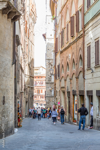 Fototapeta Naklejka Na Ścianę i Meble -  Alley with tourists in Siena, Italy