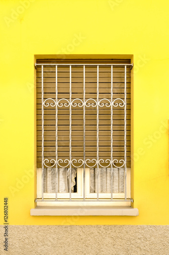 Window, Italian style window, Window with curved steel or window with grid. Bright vivid color of yellow in Italian style. (Vivid Bright Yellow / Toned Photo) photo