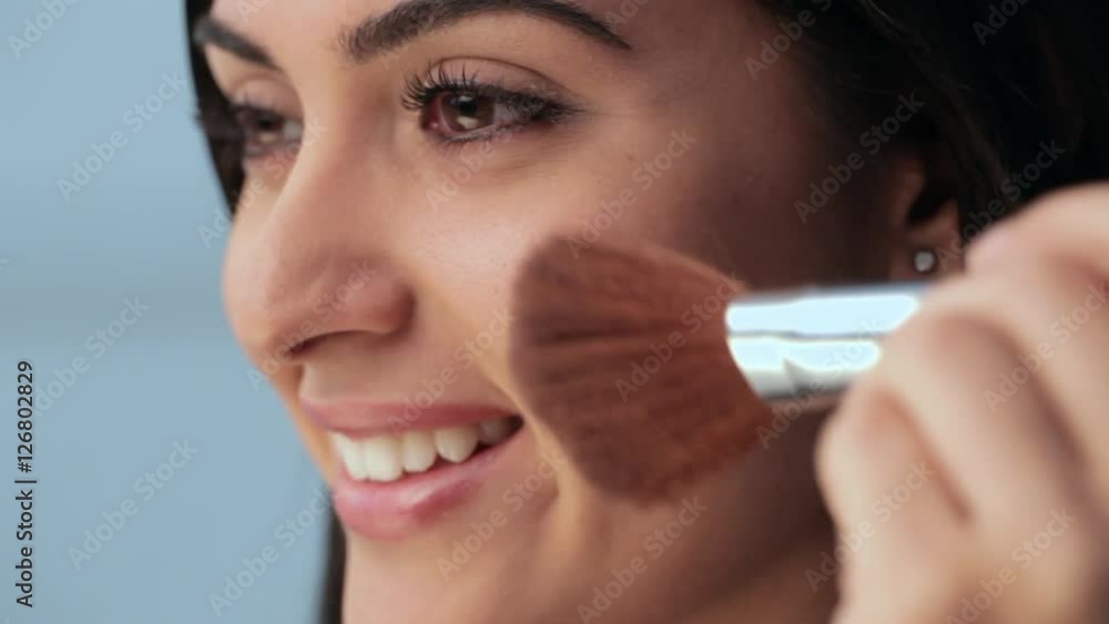 CU Young woman applying blush then looking at camera, studio shot CU Young woman applying blush then looking at camera, studio shot