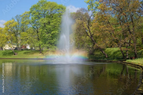 The iridescent fountain on the city channel in the sunny May afternoon. Park of the Bastionny hill, Riga. Latvia
