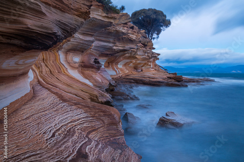 Painted Cliffs on Maria Island National Park, Tasmania, Australia. Eroded layers of iron oxide form interesting patterns in the coastline. photo