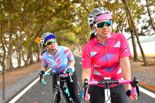 Two Women ride bike on countryside, healthy lifestyle concept and sport motivation idea
